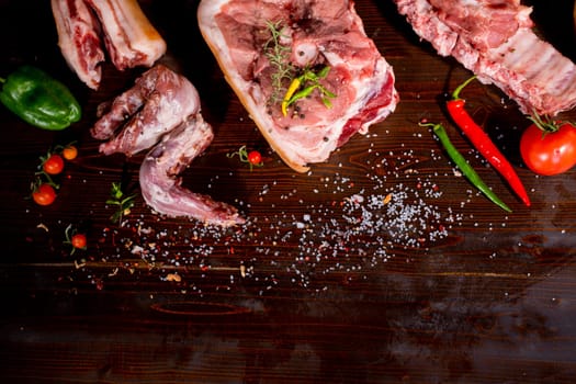 Set of raw meat. Pork meat on black stone background with spices and herbs. Top view. Rustic style. High quality photo