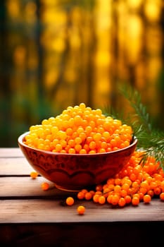 Sea buckthorn in a bowl against the backdrop of the garden. Selective focus. Food.