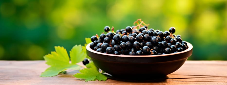 Black currant berries in a bowl against the backdrop of the garden. Selective focus. Food.