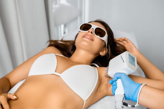 Laser epilation of armpits for a young attractive woman in bikini.