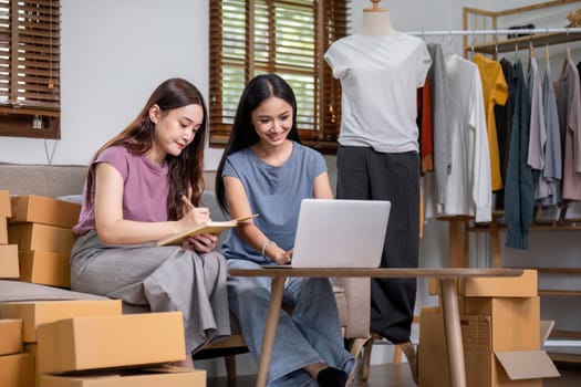 Asian couple chatting livestream to sell clothes and showing clothes to customers while selling at home..