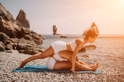 Woman sea yoga. Back view of free calm happy satisfied woman with long hair standing on top rock with yoga position against of sky by the sea. Healthy lifestyle outdoors in nature, fitness concept.