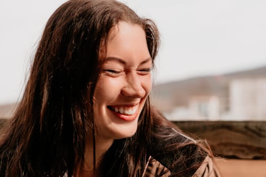 Happy young smiling woman with freckles outdoors portrait. Soft sunny colors. Outdoor close-up portrait of a young brunette woman and looking to the camera, posing against nature background.