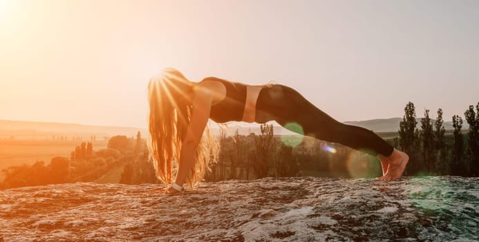 Well looking middle aged woman with long hair, fitness instructor in leggings and tops doing stretching and pilates on the rock near forest. Female fitness yoga routine concept. Healthy lifestyle.