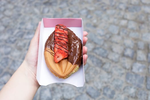 Festival Street Food. Genital Vagina, Vulva Shaped Waffle With Berries, Dark Chocolate Decorated With Berries In Human Hand Outdoor. Sweet Cookie Horizontal Plane.