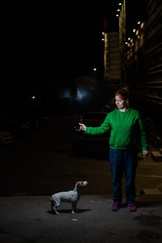 Woman sheltering jack russell terrier dog under umbrella from rain