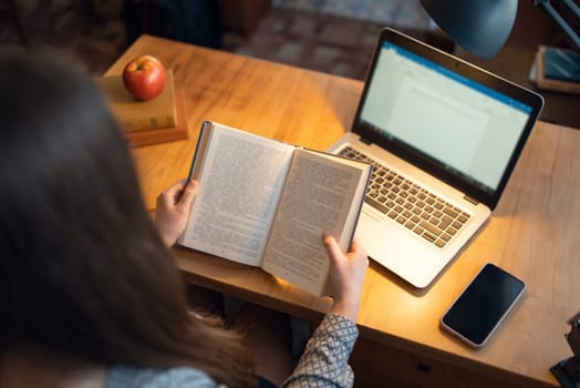 Student reading literature, using laptop to take notes