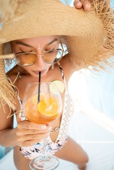 sexy young girl in a straw hat on vacation drinks a cocktail, smiles, gets high and enjoys life in the summer