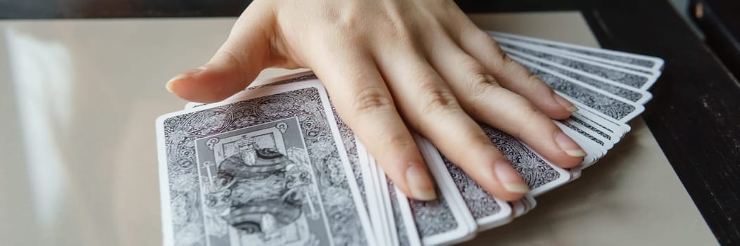 TVER, RUSSIA - FEBRUARY 11, 2023. Tarot cards, Tarot card divination, esoteric background. A woman makes a layout on the cards at the table. Divination, predictions on tarot cards