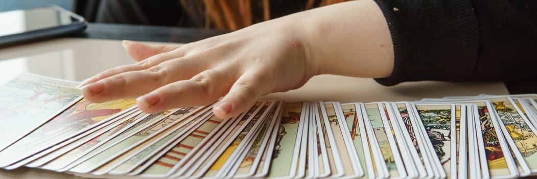 TVER, RUSSIA - FEBRUARY 11, 2023. Tarot cards, Tarot card divination, esoteric background. A woman makes a layout on the cards at the table. Divination, predictions on tarot cards