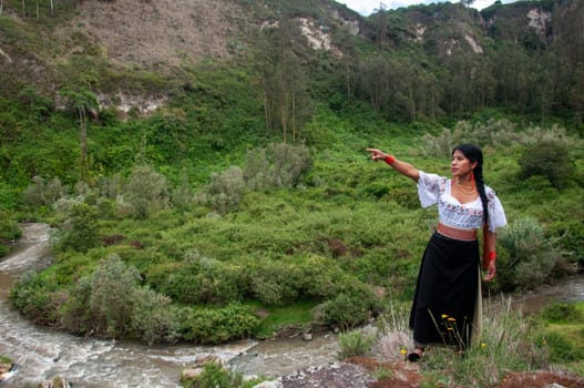 copyspace of a beautiful indigenous woman from otavalo, ecuador pointing with her arm to the left side of the photo . earth day. High quality photo