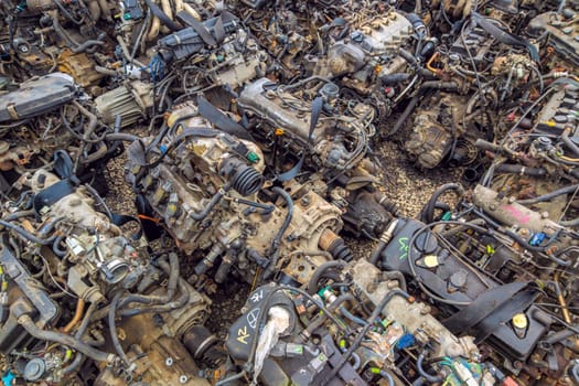 many used internal combustion engines with gearboxes on the ground of junkyard at cloudy day