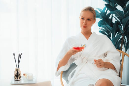 Beauty or body treatment spa salon vacation lifestyle concept with woman wearing bathrobe relaxing with drinks in luxurious hotel spa or resort room. Vacation and leisure relaxation. Quiescent