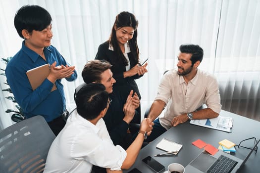 Diverse group of office employee worker shake hand after making agreement on strategic business marketing meeting. Teamwork and positive attitude create productive and supportive workplace. Prudent