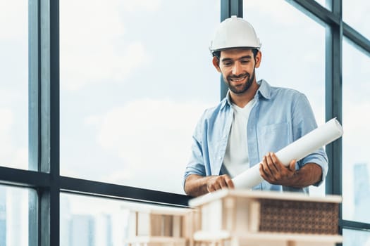 Smart civil engineer standing, walking while looking at house model and architectural equipment. Engineer with safety helmet standing near city view while standing near building model. Tracery.