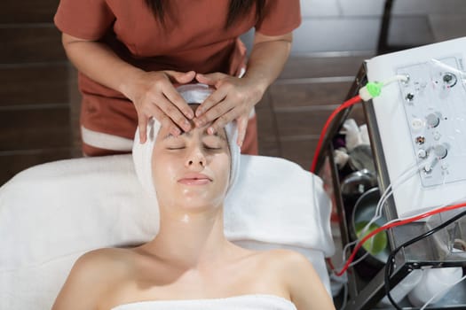 Beautiful young women with beautiful skin having facial massage surrounded by professional therapist using beauty electrical equipment. Top view. Healthy and beauty concept. Tranquility.