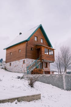 Wooden two-story house with a woodpile in a snowy village. High quality photo