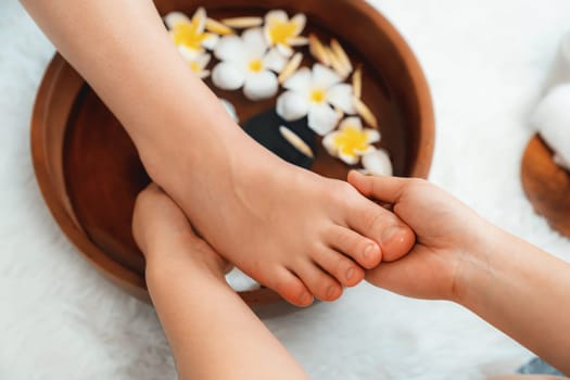 Woman indulges in blissful foot massage at luxurious spa salon while masseur give reflexology therapy in gentle day light ambiance resort or hotel foot spa. Quiescent