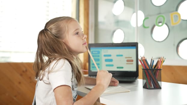 Cute student thinking while writing or doing homework by using laptop screen display engineering coding program or programing system. Caucasian girl thinking while working or doing report. Erudition.