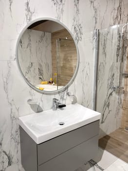 Modern restroom interior with stone gray tiles. Contemporary interior of public toilet. minimal interior with white tiles, round mirrors. Perspective of men's restroom. commercial bathroom.