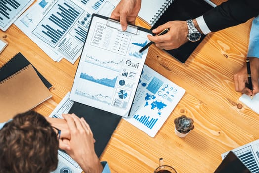 Top view diverse group of business analyst team analyzing financial data report paper on meeting table. Chart and graph dashboard by business intelligence analysis. Meticulous