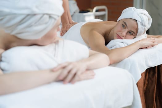 A portrait of two attractive young women with beautiful skin in white towel having a back massage by professional masseur at traditional spa salon. Beauty and healthy. Tranquility.
