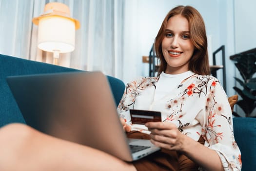 Young happy woman buy product by online shopping at home while ordering items from the internet with credit card online payment system protected by utmost cyber security from online store platform