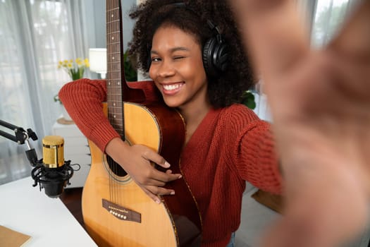Host channel in musician of young African American with selfie for fans, broadcasting on smartphone in private studio. Decoration of equipment of headsets and recording microphone. Tastemaker.