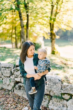 Mom with a little girl in her arms walks in the autumn park. High quality photo