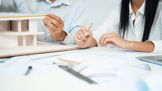 Professional engineer measures house model while skilled designer writes down in blueprint. Work together, collaboration, cooperate. Creative design and team working concept. Closeup. Immaculate