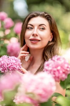 Hydrangeas Happy woman in pink dress amid hydrangeas. Large pink hydrangea caps surround woman. Sunny outdoor setting. Showcasing happy woman amid hydrangea bloom