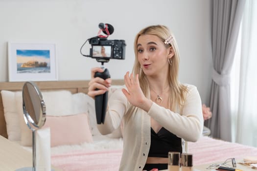 Young woman making beauty and cosmetic tutorial video content for social media. Beauty blogger smiles to camera while showing how to beauty care to audience or followers. Blithe