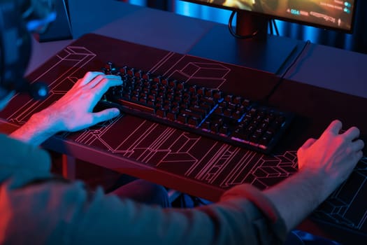 Cropped host channel of young gaming streamer playing fighting Moba at battle arena game with multiplays team on blurred pc screen with back side image at neon digital light modern room. Gusher.