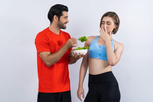 Full body length gaiety shot athletic and sporty young couple with healthy vegan food in standing posture on isolated background. Healthy active and body care by vegetarian lifestyle.