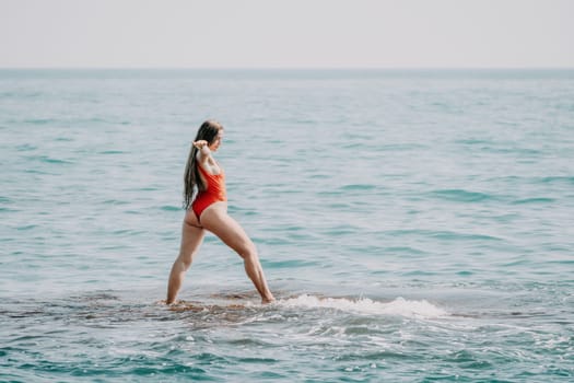 Woman sea yoga. Back view of free calm happy satisfied woman with long hair standing on top rock with yoga position against of sky by the sea. Healthy lifestyle outdoors in nature, fitness concept.