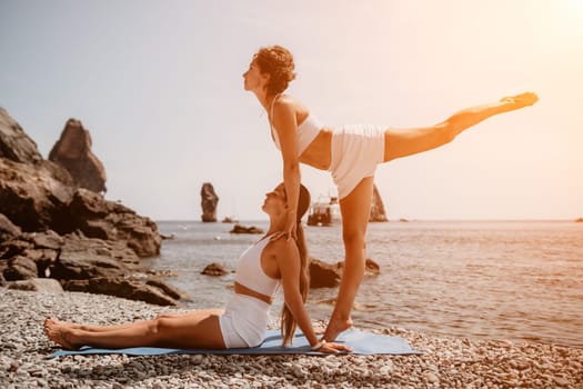 Woman sea yoga. Back view of free calm happy satisfied woman with long hair standing on top rock with yoga position against of sky by the sea. Healthy lifestyle outdoors in nature, fitness concept.