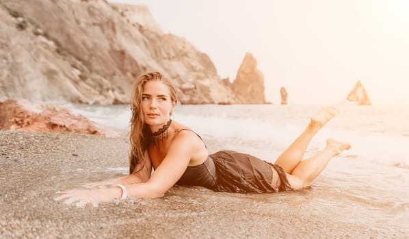 Woman travel sea. Young Happy woman in a long red dress posing on a beach near the sea on background of volcanic rocks, like in Iceland, sharing travel adventure journey