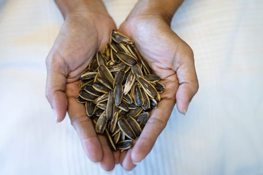 Handful of rich sunflower seeds. Close-up view of roasted sunflower seeds. Woman holding a pile of sunflower seeds.