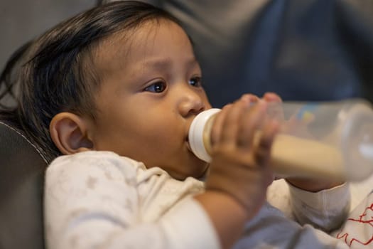 Baby Drinking Milk From The Bottle.  Close up of feeding baby with milk infant hold bottle.