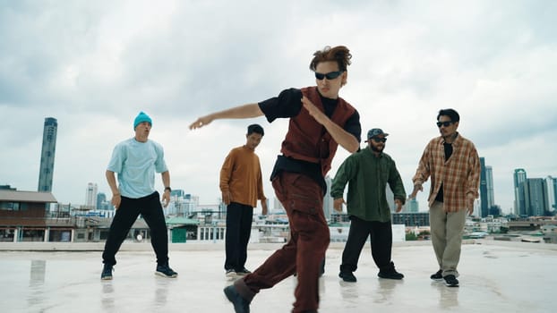 Professional break dance team practice B-boy dance while multicultural friends at rooftop. Young modern dancing group doing hip hop movement. Style,fashion,action. Outdoor sport 2024. Endeavor.