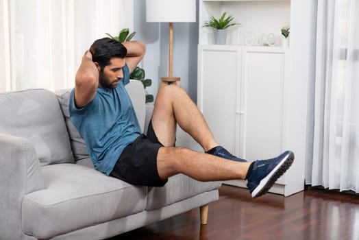 Athletic body and active sporty man using furniture for effective targeting muscle gain exercise at gaiety home exercise as concept of healthy fit body home workout lifestyle.