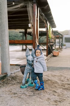 Little smiling girl leaned against the pack donkey statue. High quality photo