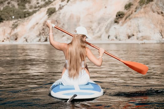 Close up shot of beautiful young caucasian woman with black hair and freckles looking at camera and smiling. Cute woman portrait in a pink bikini posing on a volcanic rock high above the sea