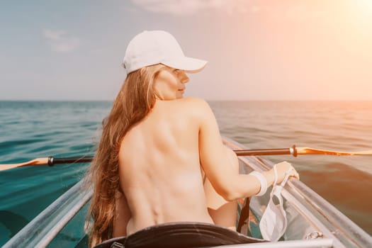 Woman in kayak back view. Happy young woman with long hair floating in transparent kayak on the crystal clear sea. Summer holiday vacation and cheerful female people having fun on the boat.