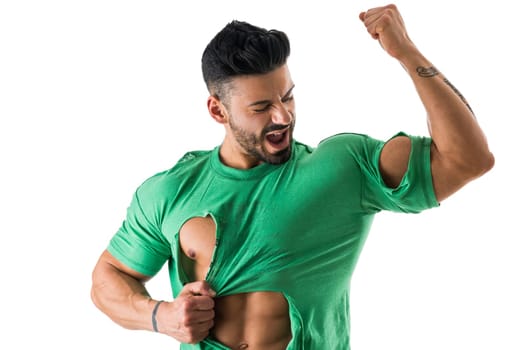 Young handsome male in jeans and torn t-shirt showing bicep and smiling on white background.