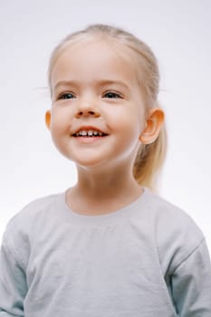 Portrait of a little smiling girl in joyful anticipation on a gray background. High quality photo