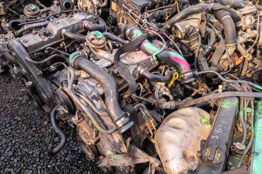 many used internal combustion engines with gearboxes on the ground of junkyard at cloudy day