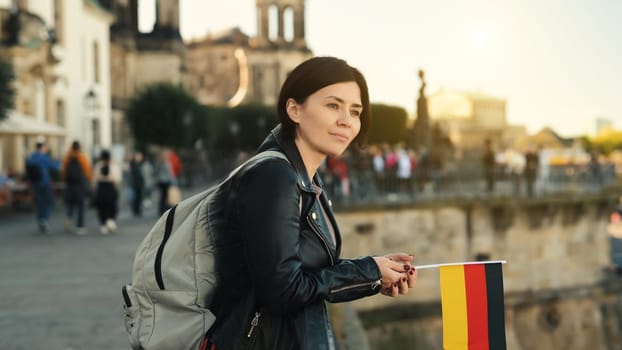 Young Woman Holds German Flag In Hand, With Blurred City Background In Autumn