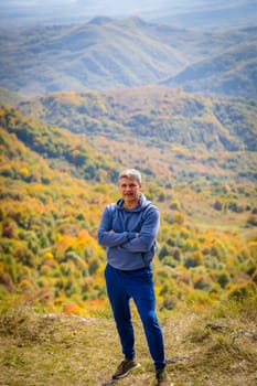 Man enjoying the view of autumn mountains, feeling the tranquility and majesty of nature