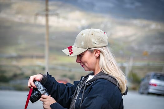 Young woman taking pictures of beautiful mountains with camera, majesty of nature and photography